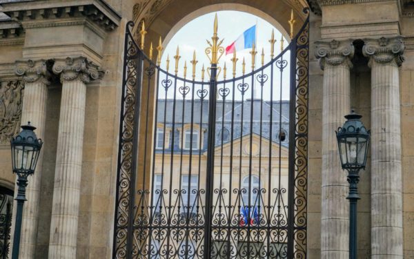 Paris, France - Entrance gate of the Élysée Palace, seat of the Presidency of the French Republic and residence of the French head of the State, adorned with French flags