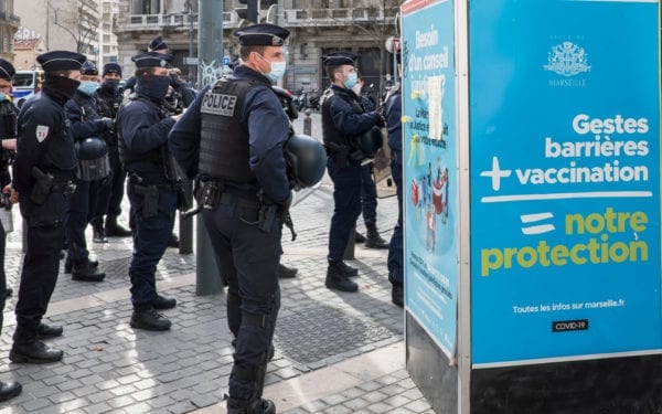 A group of French police officers stand next to a pro-vaccination poster in Marseille.