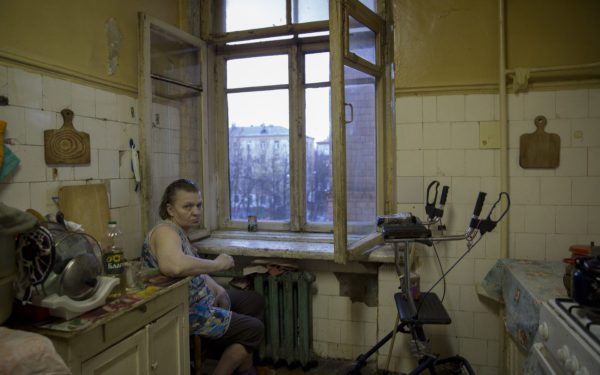 Elderly woman sits at the window in her communal apartment in Russia