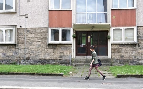 Paisley, Scotland, UK, August 2nd 2022, Student walking past council flats in poor housing estate with many social welfare problems