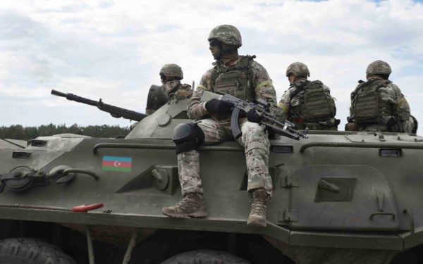 Flag of Azerbaijan on an armored personnel carrier and soldiers with machine guns.