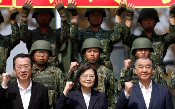 Taiwanese President Tsai Ing-wen raises her fist next to Taiwa's Defence Minister Chiu Kuo-cheng and National Security Council Secretary-General Wellington Koo, while posing for pictures among soldiers, during a visit to a military base in Chiayi, Taiwan March 25, 2023.