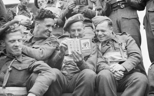 Operation Overlord (the Normandy Landings)- D-day 6 June 1944.Three British soldiers of 51st Highland Division, aboard a landing craft, pass the time by reading the booklet on France which they were issued before embarkation. (via No 5 Army Film & Photographic Unit)