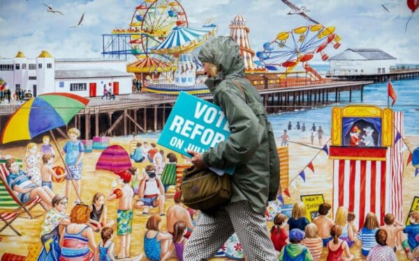 A woman carries electoral leaflets for Nigel Farage's Reform UK party in Clacton-on-Sea, England, Tuesday, July 2, 2024.