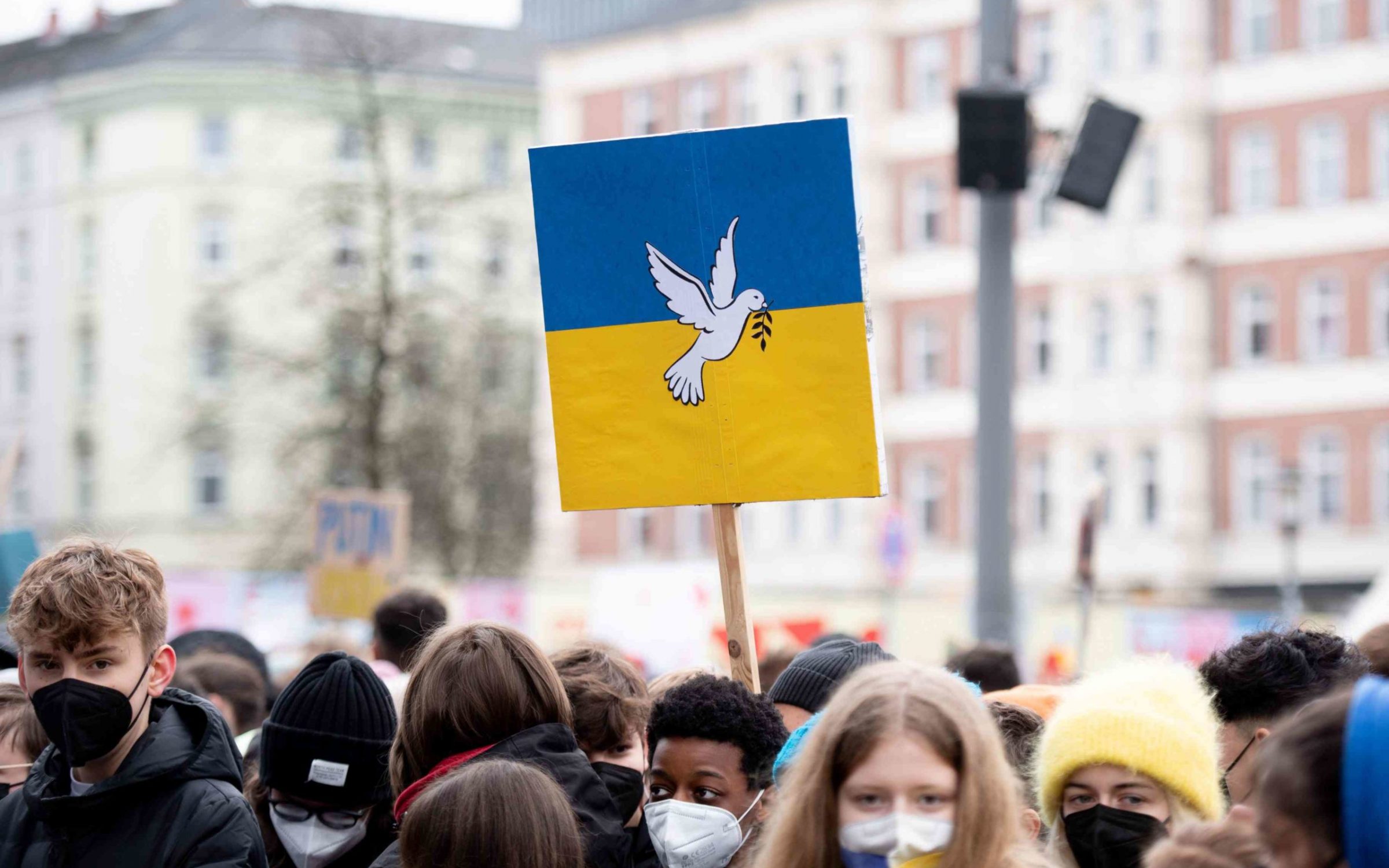 Demonstrators hold a sign in the colors of Ukraine with a dove of peace during a rally at Spielbudenplatz.
