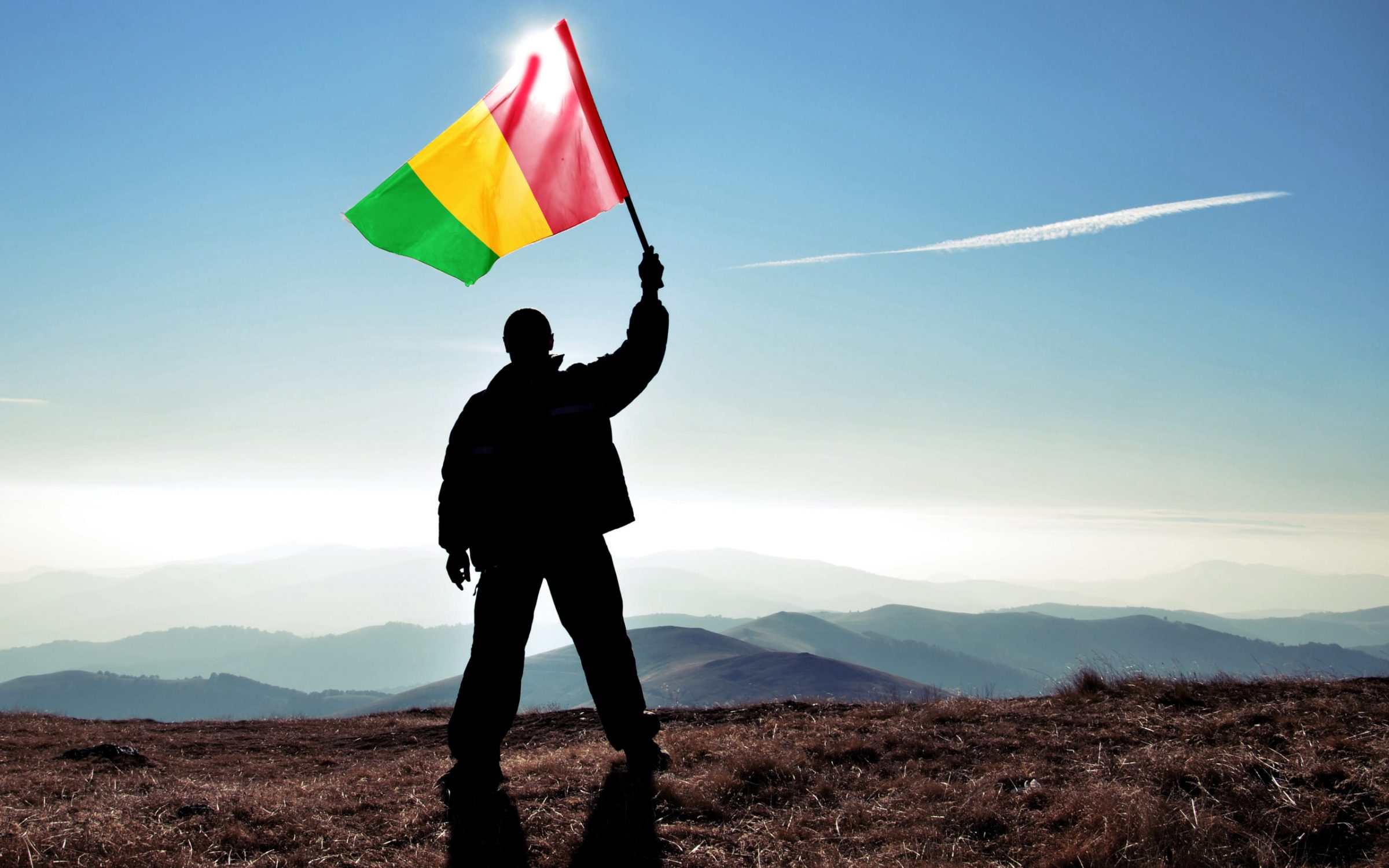 Successful silhouette man winner waving Mali flag on top of the mountain peak