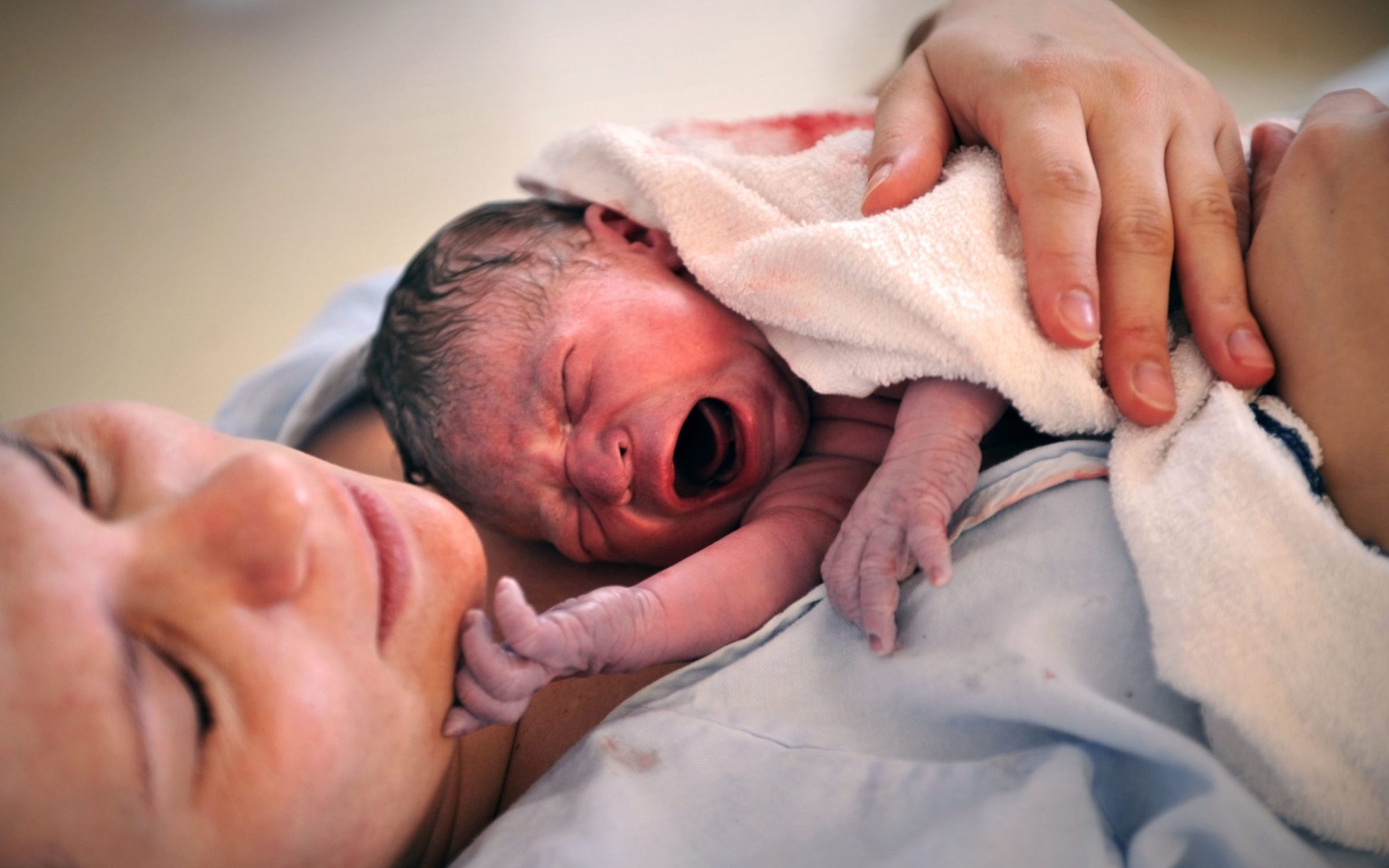A newborn baby held by his mother.