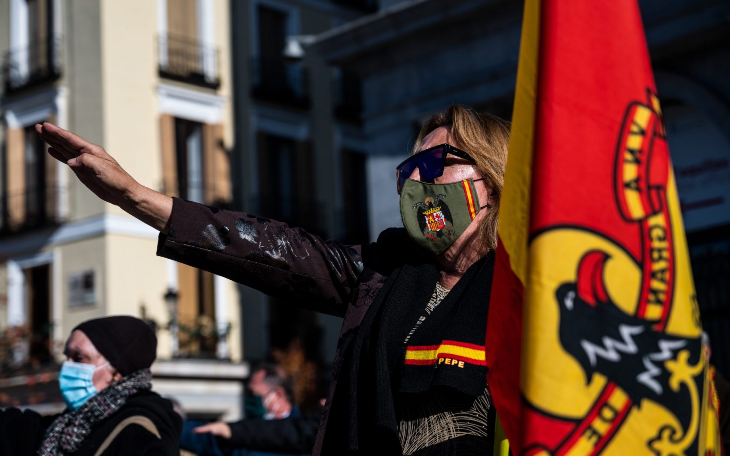A far right wing supporter of Franco wearing a mask with the pre-constitutional symbol raising her hand making a fascist salute and holding a pre-constitutional flag during a rally to commemorate the 45th anniversary of the death of Spanish former dictator Francisco Franco at Plaza de Oriente. Franco’s forces triumphed in the Spanish Civil war of 1936-1939.