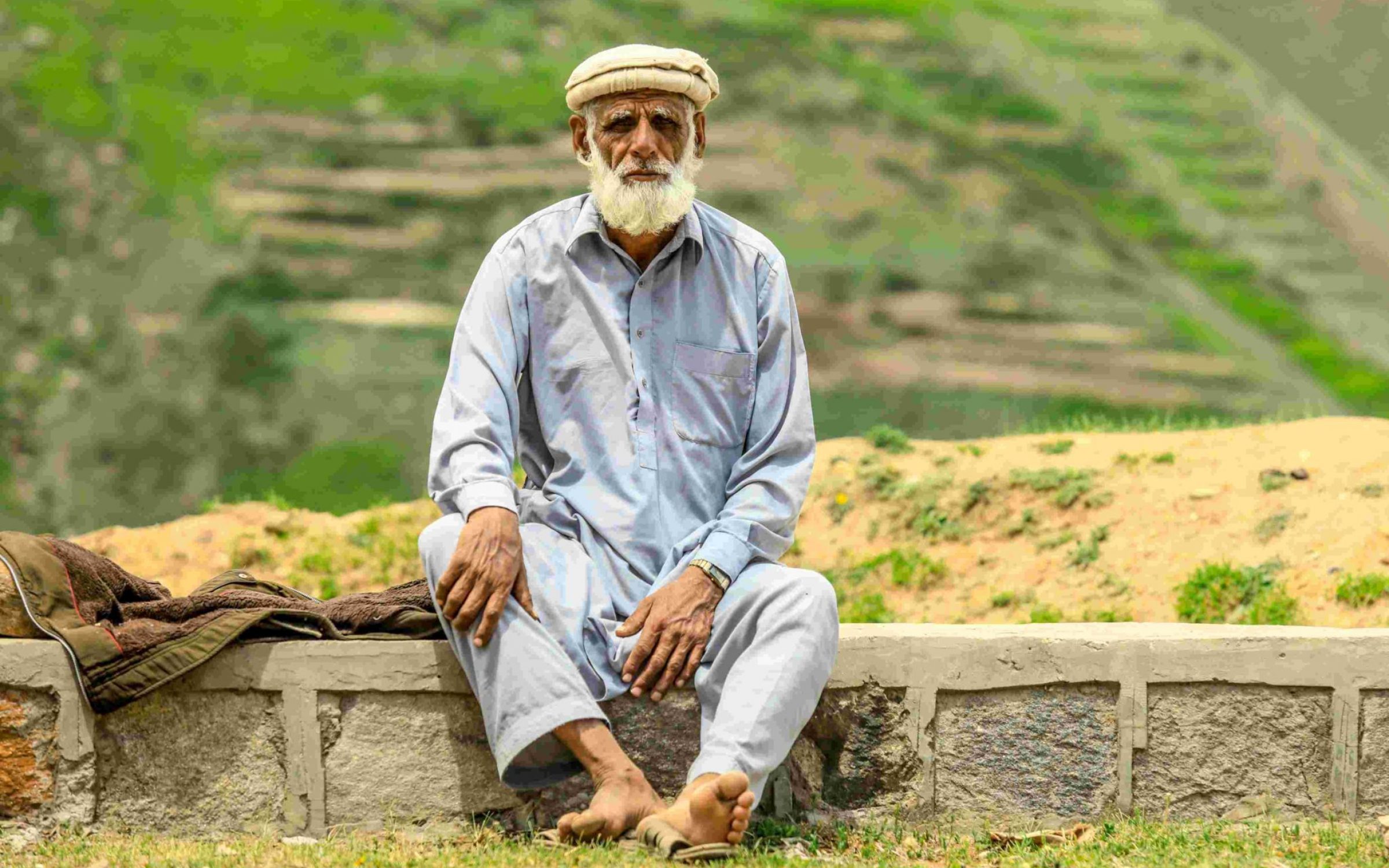An old Afghan man sits by the road