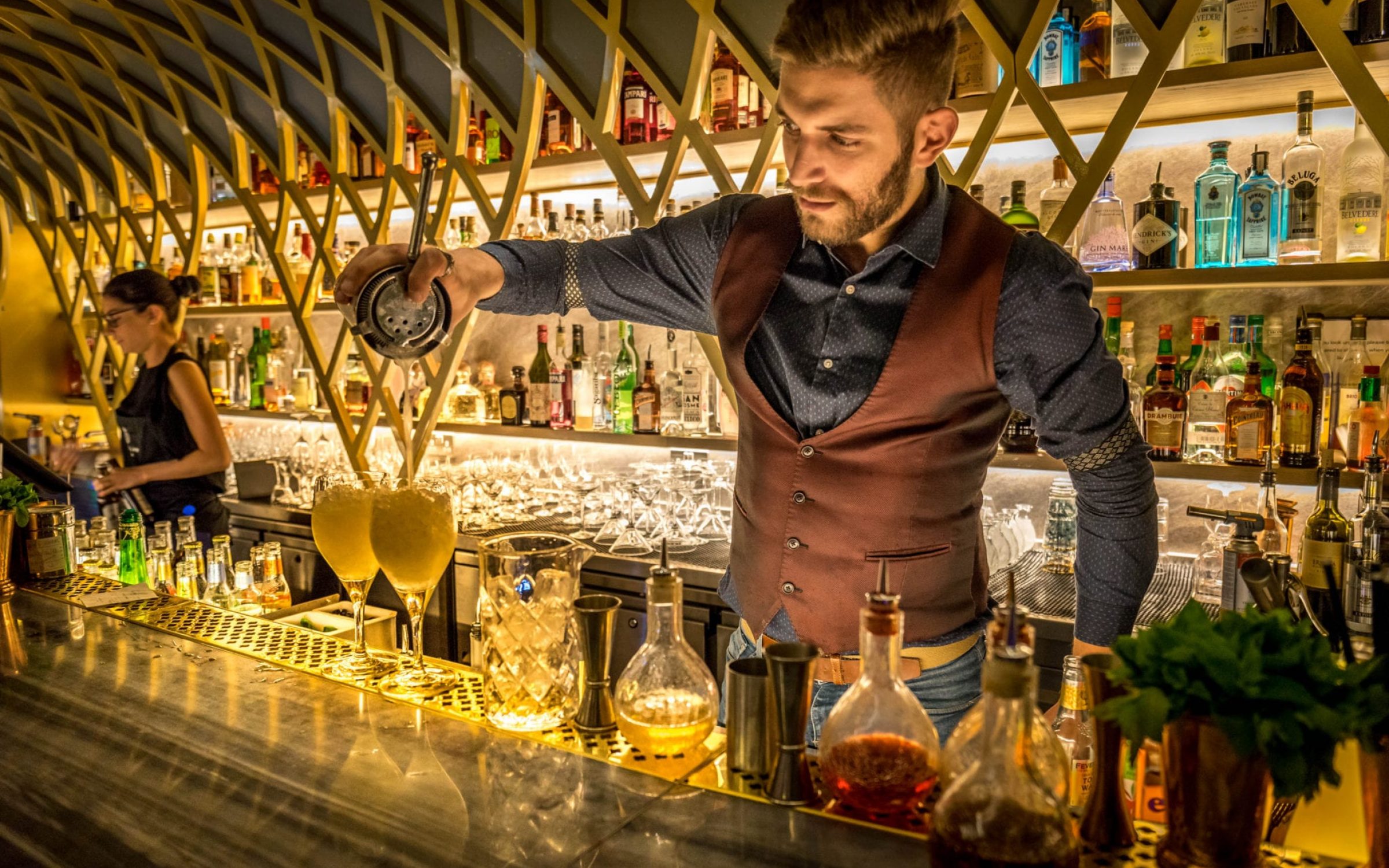A smartly dressed barman serving cocktails