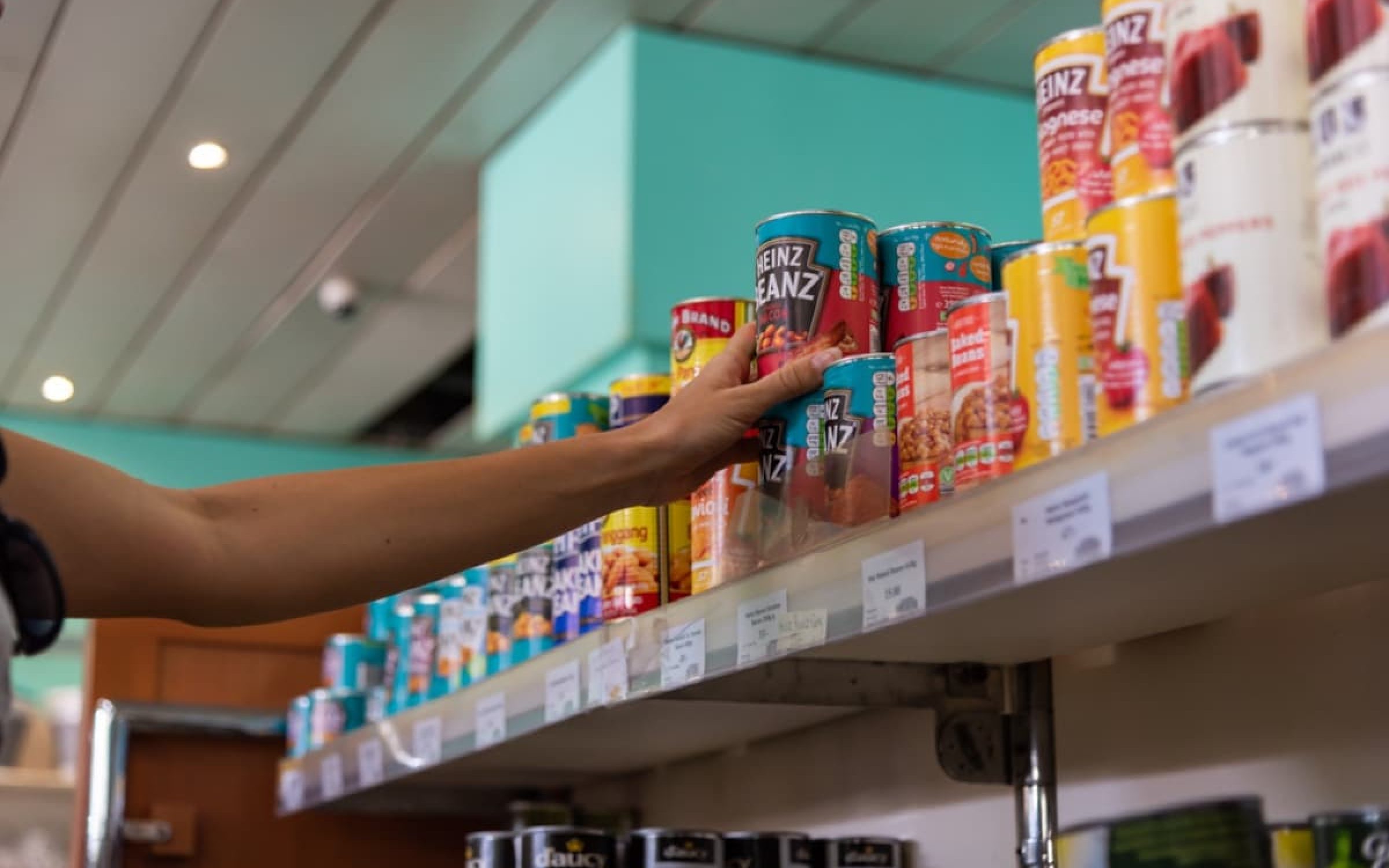 Victoria, Seychelles - January 7, 2020: Hand taking Heinz conserved beans from the shelve at the super market.