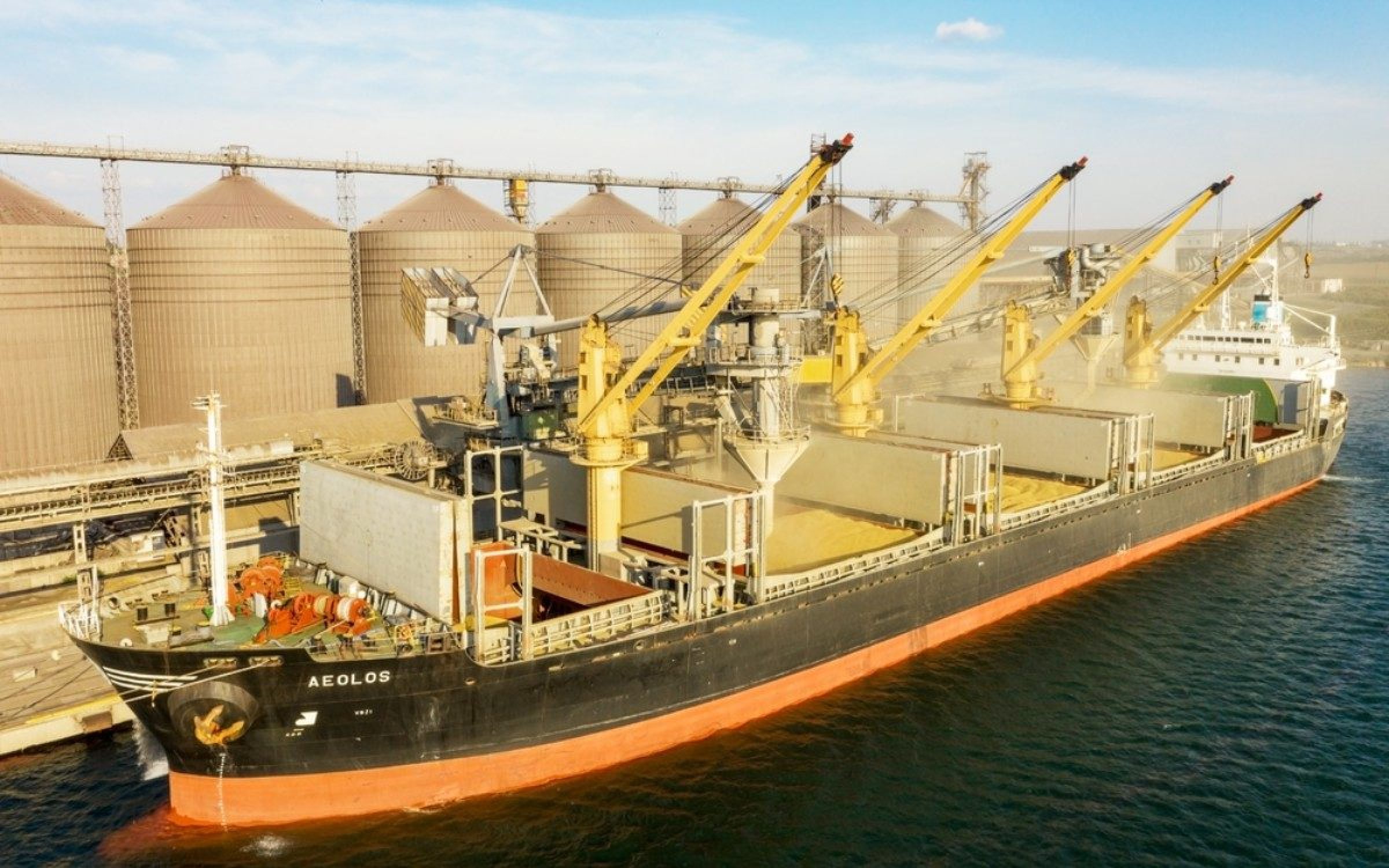 ODESSA, UKRAINE - August 9, 2021: Loading grain into holds of sea cargo vessel through an automatic line in seaport from silos of grain storage. Bunkering of dry cargo ship with grain