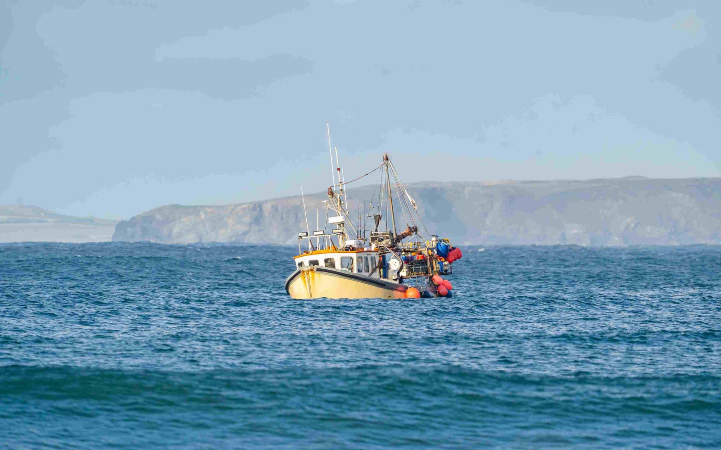 Yellow British fishing boat trawler alone in the English channel islands waters after leaving EU with no French fisherman boats or nets in view.