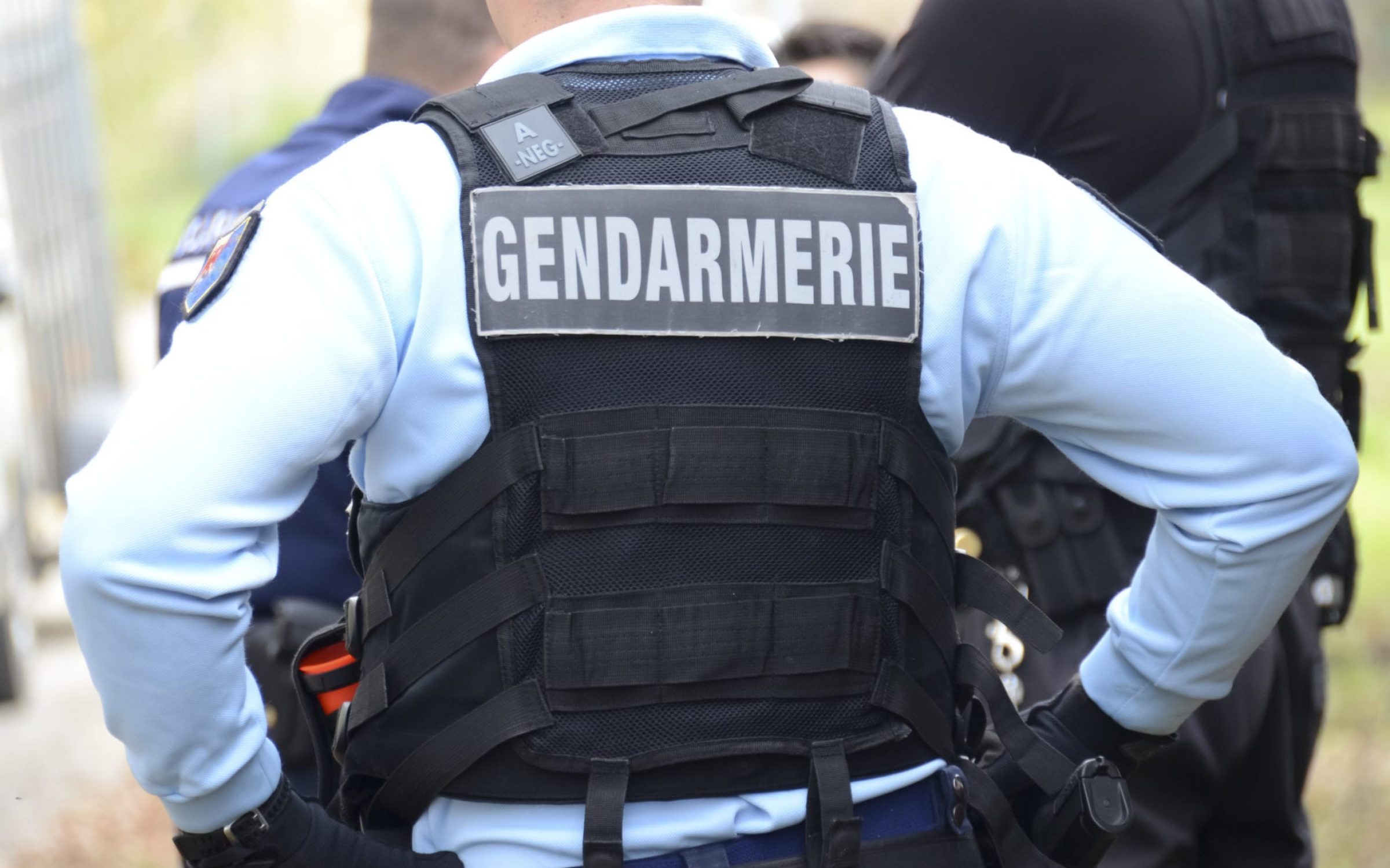French Gendarmerie police man stands with hands on hips and back to camera